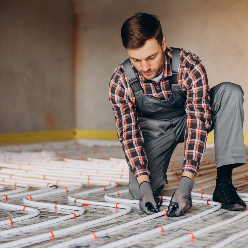 Service man instelling house heating system under the floor
